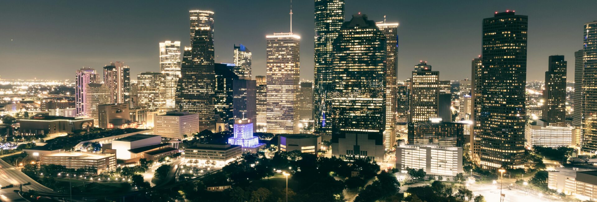 Stunning aerial view of Houston's illuminated skyline featuring skyscrapers and highways at night.